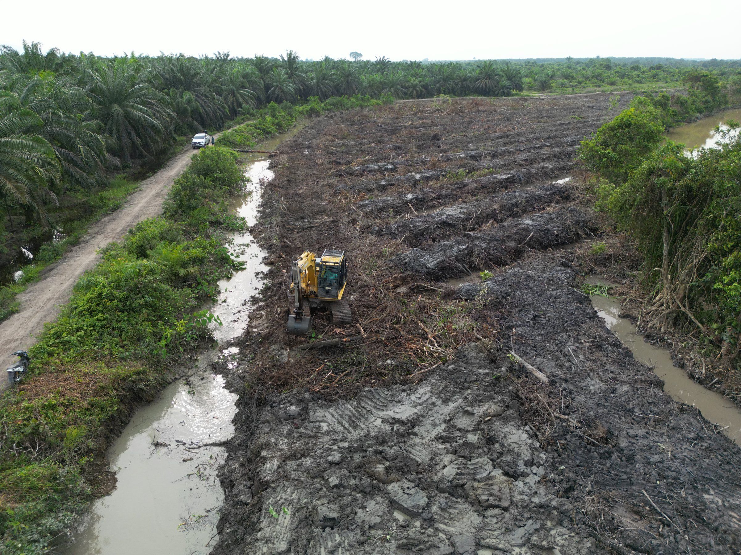 Excavator Komatsu menggali parit di samping lahan yang baru dibuka di Tungkal Ulu, Tanjung Jabung Barat