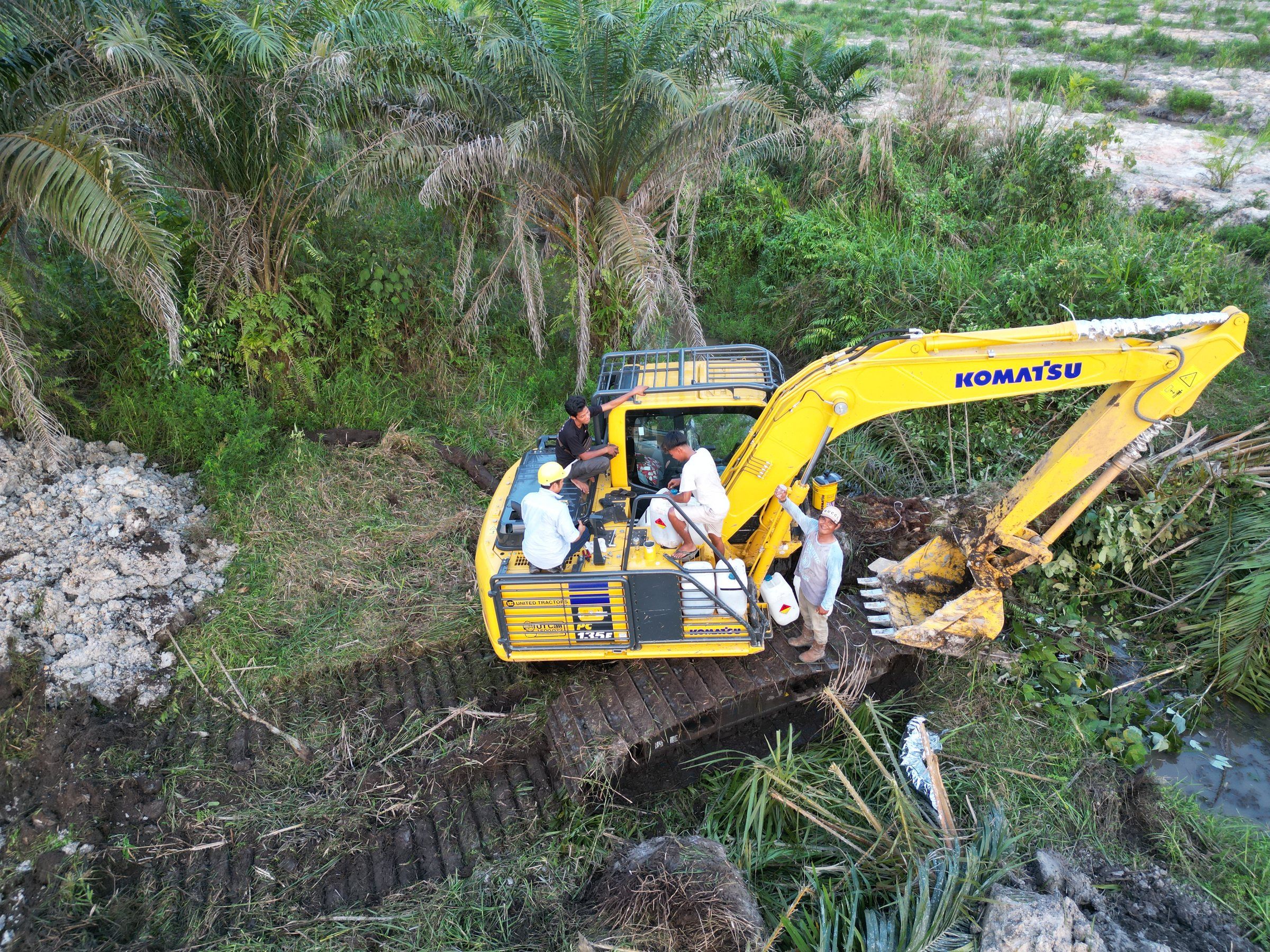 Foto udara tim Medha Karya di excavator Komatsu PC135F, di tepi parit kebun sawit